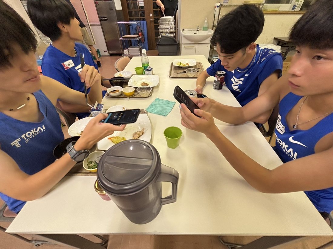 食堂でアプリを確認する選手たち